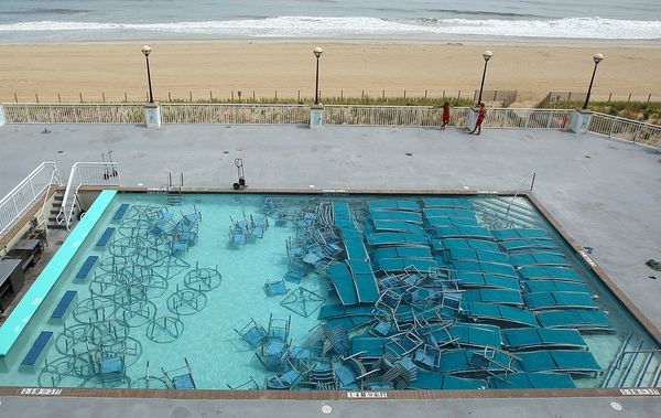 a swimming pool filled with lounge chairs and tables in preparation for a hurricane